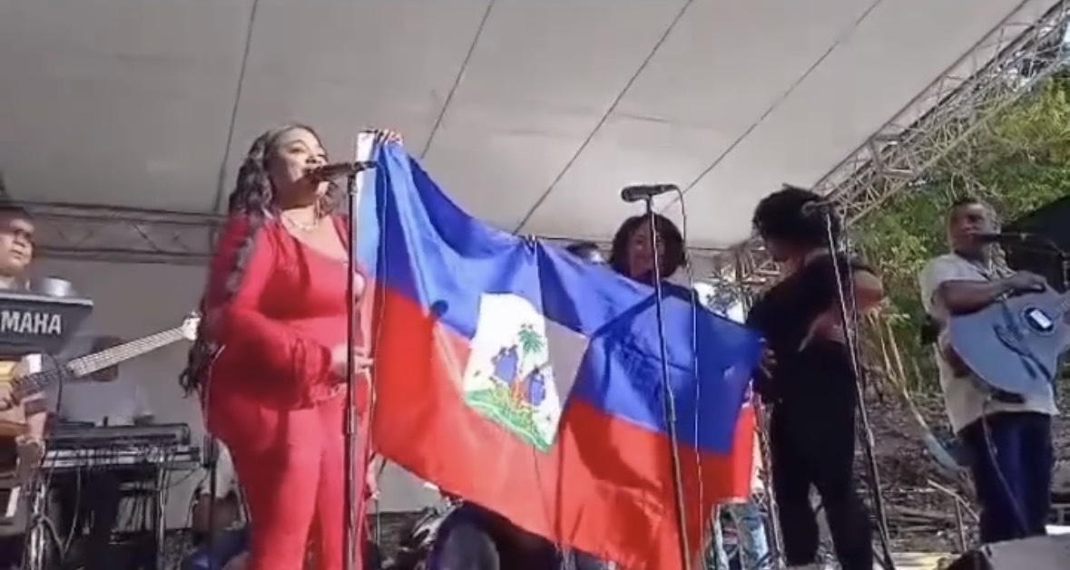 Katty Cumbe despliega bandera de Haití durante presentación musical